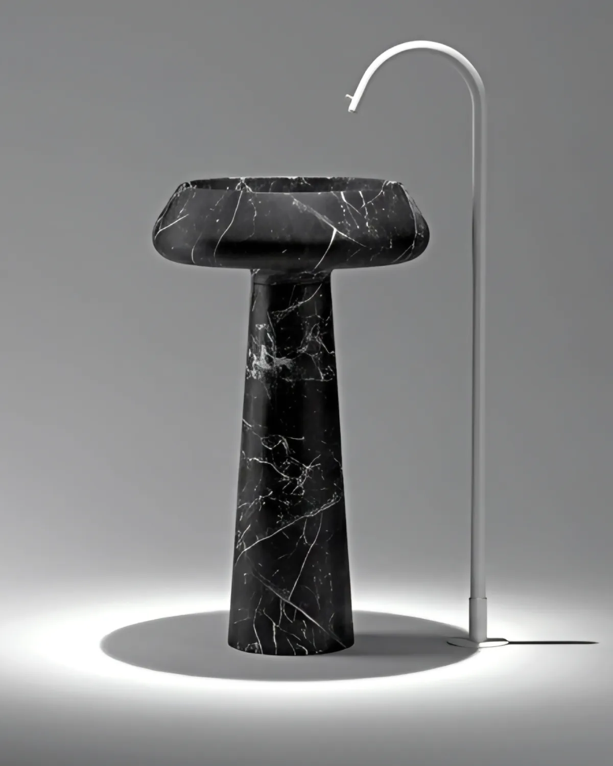 Black Nero Marquina marble pedestal wash basin with a wide shallow bowl and tall floor tap
