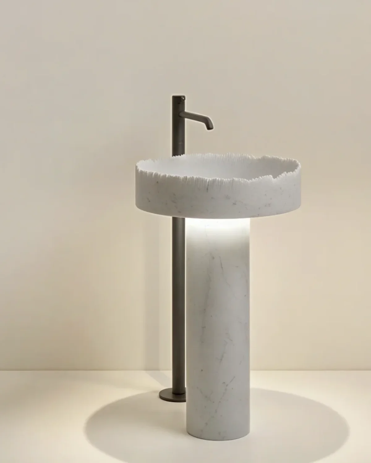 White marble pedestal wash basin with a hand-chiselled raw rim on a honed cylinder