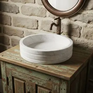 Cream-colored stone wash basin with a minimalist round design, sitting on a dark quartz countertop